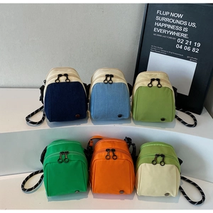 Detail view of mini crossbody bags featuring dual zippers and polka dot woven straps