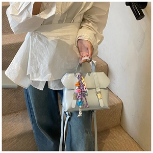 Detail of light blue leather handbag featuring colorful letter charms and gold metal buckles