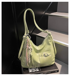 Detail of light green faux leather hobo bag with tassel and metal buckle on black steps