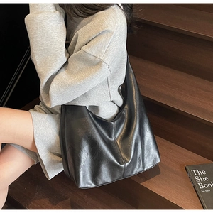 Close-up of black PU leather tote bag showing textured stitching and half-moon structure