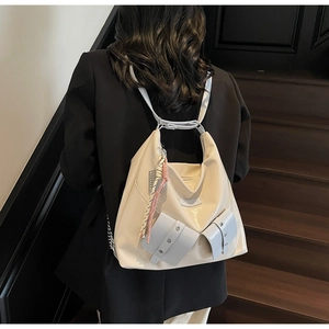 Modèle portant un sac cabas en cuir verni crème et bleu avec détails de franges