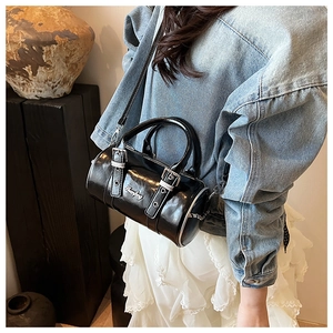 Detail of black glossy cylindrical Boston bag with contrast stitching and silver logo