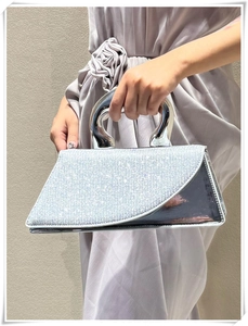 Detailed close-up of silver rhinestone handbag featuring a curved metal handle