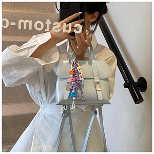 Detail of light blue PU leather backpack with silver buckles and rainbow bead charm