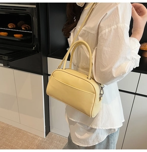 Close-up of a pale yellow lychee texture bowling handbag worn with a white shirt
