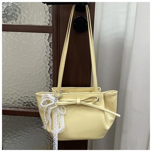 Détail du sac seau plissé crème avec nœud, ruban en dentelle et breloque en perles