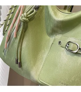 Macro detail of glossy green tote fabric with metal buckle and branded texture