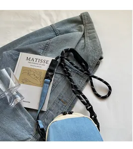 Close-up of light blue denim shell bag featuring smooth woven shoulder strap and zipper