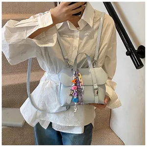 Detail of light blue faux leather bucket bag with alphabet beads and purple braided charm