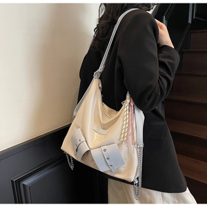 Détail du sac crème avec poches bleues, chaîne argentée et pompons colorés élégants