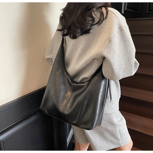 Side view of a black minimalist PU leather tote bag with vertical stitching and smooth finish
