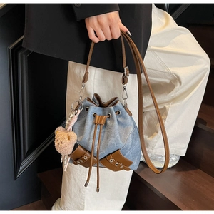 Detailansicht der Jeans-Beuteltasche mit braunem PU-Lederbesatz und Bären-Anhänger