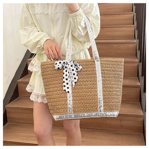 Detail of straw woven tote bag with silver sequin handles and polka dot bow accessory