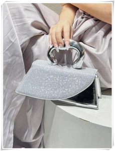 Detailed close-up of a luxury silver rhinestone handbag with a unique metal handle