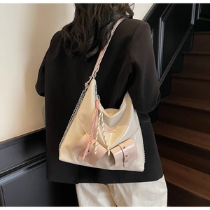 Détail d'un sac cabas crème avec des poches roses et une chaîne en métal élégante