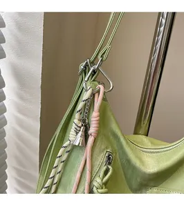 Close-up of light green tote bag detail with decorative striped knot and metal charm