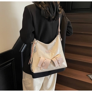 Détail d'un grand sac cabas crème avec accents roses et pendentif à pampilles chic
