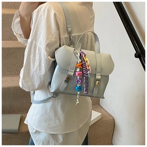 Detail of light blue PU leather backpack with silver buckle and colorful letter charm