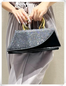 Detail of luxury rhinestone evening bag with gold metal handle and asymmetric flap design