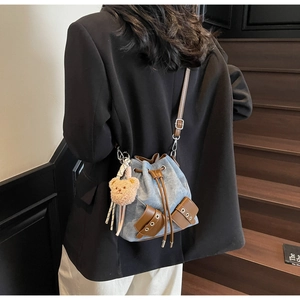 Details der Vintage-Jeans-Beuteltasche mit braunem Lederbesatz und Plüschbär-Anhänger
