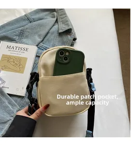 Detail showing beige canvas crossbody bag with front pocket holding a smartphone