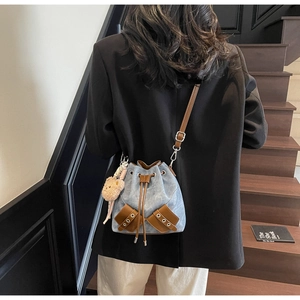 Detail der Bucket Bag aus gewaschenem Denim mit braunen Ledertaschen und Bärenanhänger