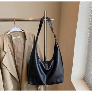 Close-up of black PU leather hobo bag with gold buckle on a brown blazer outfit