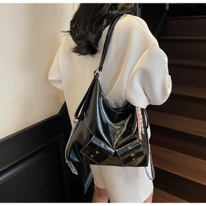 Détail du sac hobo en cuir brillant noir avec chaîne argentée sur mannequin en sweat blanc