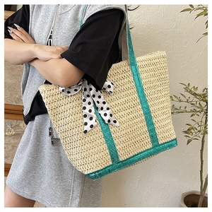 Détail d'un sac cabas en paille tissé avec paillettes vertes et nœud à pois