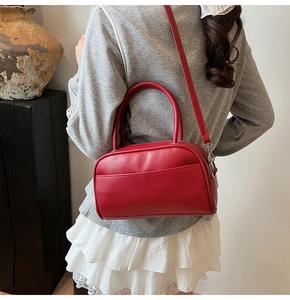 Detail of red Boston bag with pebbled texture and adjustable shoulder strap for women