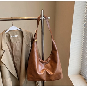 Detailed close-up of brown PU leather hobo bag with gold hardware and adjustable strap
