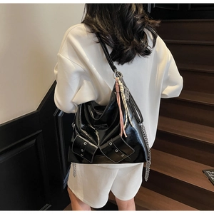 Détails d'un sac cabas noir brillant avec chaîne argentée et longues franges en cuir