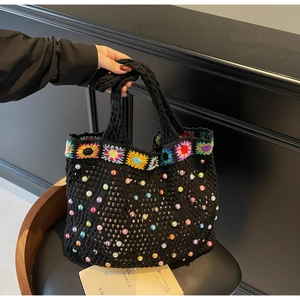 Detail of black knit tote bag with sunflower crochet patterns and colorful faux pearls