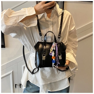 Detail view of a black glossy backpack with acrylic chains and decorative charms