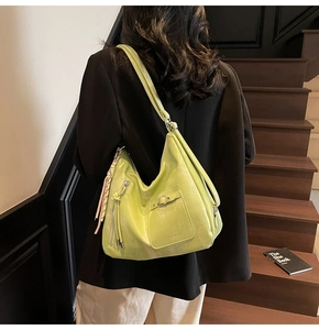 Detail of light green soft leather tote bag featuring tassel zipper and silver buckle pocket