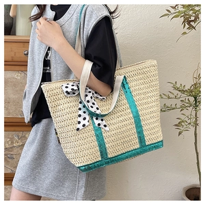 Détail du sac en paille avec paillettes bleues et ruban à pois sur la poignée tressée