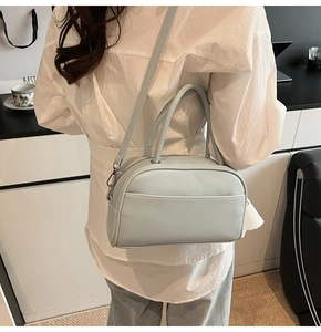 Rear view of a light blue leather pillow bag worn crossbody with dual handles