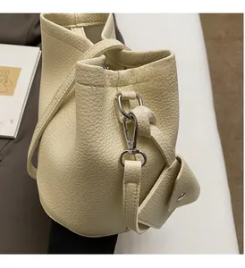Detail view of cream lychee grain leather bucket bag with silver metal hooks and mini pouch