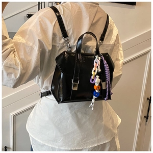 Rear view of a black glossy bucket backpack with colorful chains and woven pendants