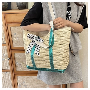 Détail d'un sac en paille avec paillettes vertes et nœud à pois élégant