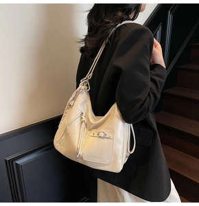 Detail of soft cream leather tote bag featuring functional front pockets and a brand logo