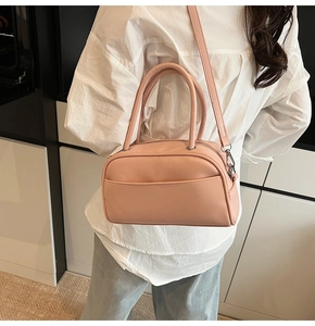 Detailed side view of pink faux leather boston bag with silver hardware on model