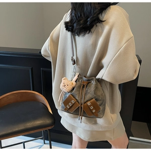 Nahaufnahme der Retro-Beuteltasche aus grauem Canvas mit Lederakzenten und Bär-Anhänger
