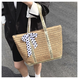 Détail du grand sac cabas en paille avec nœud à pois et poignées métallisées
