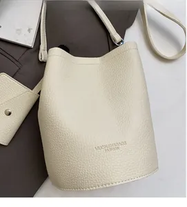 Detail of cream bucket bag showing lychee pattern leather texture and gold logo