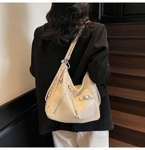 Detail of a creamy white leather tote bag featuring multiple pockets and silver buckle strap