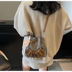 Modellansicht graue Segeltuch-Eimertasche mit braunem Lederriemen und Bärenanhänger