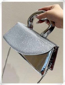 Detailed side view of silver rhinestone handbag with metallic handle and chain strap