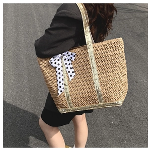Grand sac cabas en paille avec bretelles dorées et nœud à pois porté à l'épaule