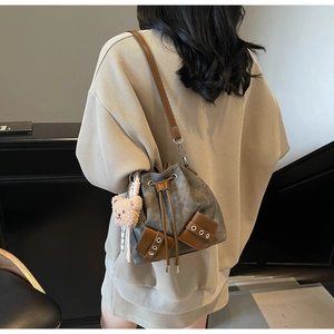 Detailsicht der Retro-Canvas-Beuteltasche mit braunem Lederbesatz und Bärenanhänger